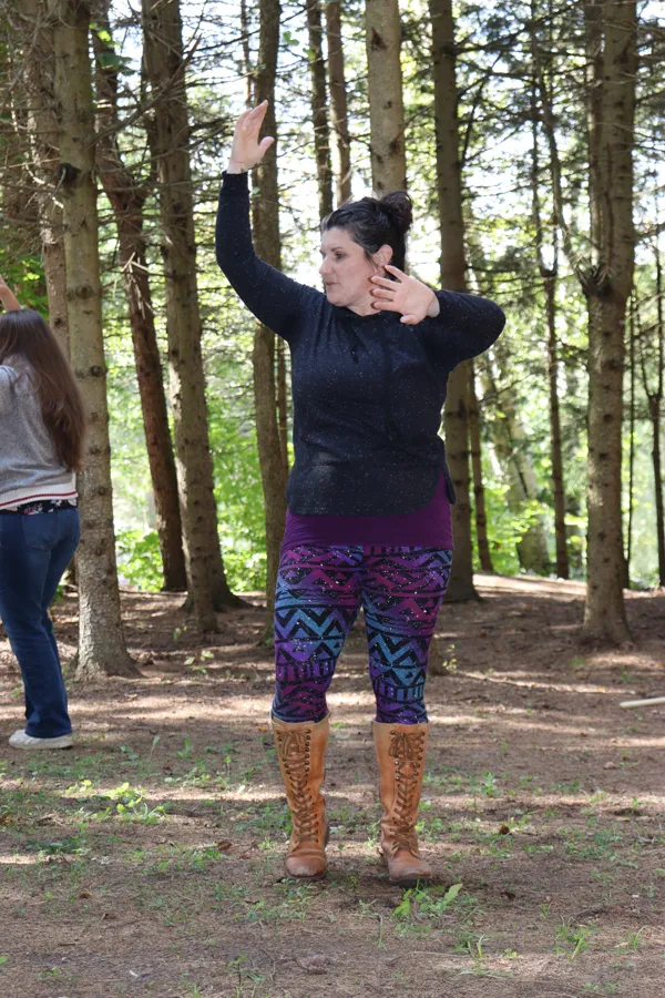 Angélique dancing in the pine forest, one arm raised