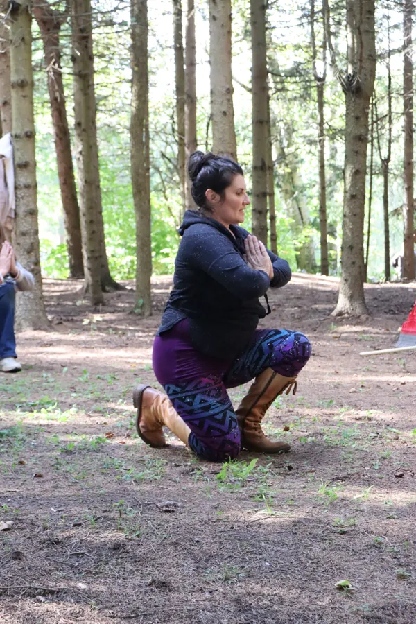 Angélique kneeling on the forest floor during a dance class