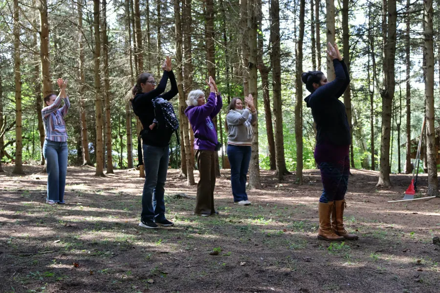 Dancers of all ages following Angélique's arm movements in the forest