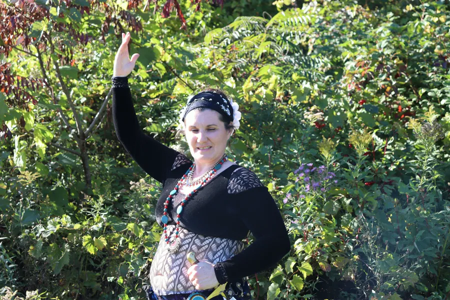 Angélique smiling, one arm raised, in front of autumn leaves