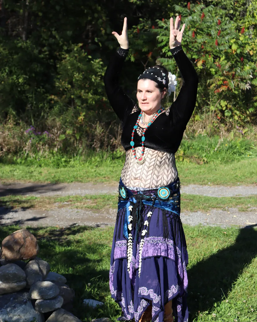 Angélique with both arms raised overhead in the sunshine